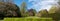 Panoramic photo of a variety of trees and shrubs in nature with blue sky in the background.