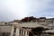 The panoramic of the Potala Palace, with the people republic of China flag inside as well as Potala Palace square, trees and meado