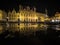 Panoramic puddle reflection of illuminated facade architecture of Bruges City Hall at main Burg square Belgium Europe