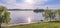 Panoramic reflection of riverbank trees, buildings and bridges