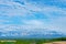 Panoramic rural landscape with mountains. Vast blue sky and white clouds over farmland field