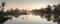 Panoramic scenery of the misty bog lake on the dawn colors