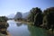 Panoramic scenic view of Nam Song Xong river amidst trees and rural karst hills landscape against blue clear sky , near Vang