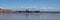 panoramic scenic view of Scarborough lighthouse and harbour reflected in the wet beach sand on a sunlit summer day