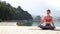 Panoramic shot of athletic woman meditating in lotus pose at seaside in morning