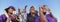 Panoramic shot of cheerful baseball players with trophy celebrating victory against clear sky