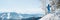 Panoramic shot of a female skier resting on top of the mountain observing nature at ski resort