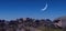 Panoramic shot of massive rocks under a starry sky with a crescent moon