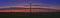 Panoramic shot of a silhouette of windmills on a field during sunset