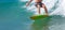 Panoramic shot of a surfer on the board in the wavy sea