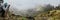 Panoramic shot of traveler making photo of amazing steep mountainous terrain with lush canyon valley on the path from Xo