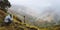 Panoramic shot of traveler making photo of amazing steep mountainous terrain with lush canyon valley on the path from Xo