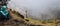 Panoramic shot of traveler making photo of amazing steep mountainous terrain with lush canyon valley on the path from Xo