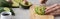 Panoramic shot of woman cutting avocado with knife on cutting board among ingredients.