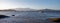 Panoramic of a small ship on a voyage on a blue seascape against a blurred skyline of mountains