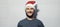 Panoramic studio portrait of cheerful man on background of white brick wall. Christmas holidays concept. Young guy with Santa hat.