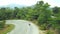 Panoramic top view of the jungle in Phuket, Thailand. The drone goes down to the road, where you can see moving motobikes, forest