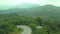 Panoramic top view of the jungle in Phuket, Thailand. The drone goes down to the road, where you can see moving motobikes, forest