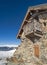 Panoramic view across snow covered slope on alpine mountain with small house