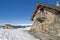 Panoramic view across snow covered slope on alpine mountain with small house