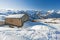 Panoramic view across snow covered slope on alpine mountain with small house