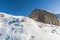 Panoramic view across snow covered slope on alpine mountain with small house