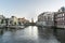 Panoramic view of Amsterdam from the Amstel river, showing Munttoren tower and summer blue skies.