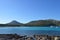 Panoramic view of beach, boats, mountains, cliffs, sea and blue sky.