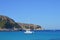 Panoramic view of boat, mountains, cliffs, sea and blue sky.