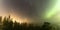 Panoramic view of brilliant green Aurora shining over Swedish foggy forest landscape, light rays from a village and Northern