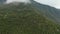 Panoramic view of a cloudscape over the mountains with huge green tops of the trees. Clouds are flying over a hill