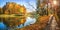 Panoramic view of colorful autumn trees and a path along the pond in Tsaritsyno Park in Moscow