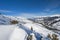 Panoramic view down snow covered valley in alpine mountain range with conifer pine trees