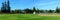 Panoramic view of an empty softball, baseball field, trees and green grass in typical american residential suburban neighborhood