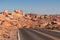 Panoramic view of endless winding empty road leading to red Aztec Sandstone Rock formations in Mojave desert, Nevada, USA