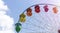 Panoramic view of the Ferris wheel at the amusement park. Colorful ferris wheel against the blue sky on a sunny day.