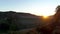 Panoramic view of field with seedlings. Shot. Top view of plantation in haze on hilly landscape at dusk. Divergent road