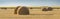 Panoramic view of field with wheat straw, hay bales and sky, rural landscape in the agriculture farm land.
