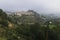 Panoramic view at a foggy morning in the hills of Polop de Marina with church and castell over green forest, Spain