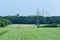 Panoramic view of a green field and high voltage towers, electricity pylons in the distant