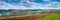 panoramic view of green winter wheat spring field  plowed lands lines  relief hilly landscape in the background