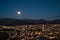 Panoramic view of Grenoble at night with the full moon in the sky and the Belledonne massif in the background