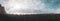 Panoramic view of groups of tourists walking around and taking photographs on a rocky beach