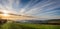 Panoramic View from hilltop of sun setting over valley shrouded in mist in Dorset,