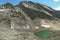 Panoramic view from Hohe Sonnblick in Austrian Alps on the mountain around. There is a small green lake at the bottom.