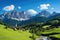Panoramic view of idyllic mountain scenery in the Alps with fresh green meadows in bloom on a beautiful sunny day in springtime