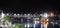 Panoramic view of an illuminated railway bridge over a calm river with light reflections at night