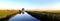 Panoramic view of the irrigation canal and the tree reflected in the water surface.