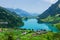 Panoramic view of lake, countryside, green alpine meadows and mountains