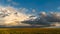 Panoramic view of a large rain cloud and an agricultural field. A huge cloud with a thunderstorm and thunder hangs over a green